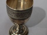 a silver cup sitting on a table next to a cell phone