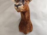 a clay sculpture of a goat head on a white surface