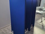 three blue partitions in a room with wood flooring