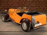 a small orange car parked in front of a brick wall