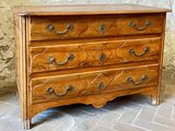 a wooden chest of drawers sitting on a brick floor