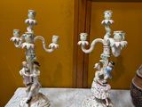 two candles that are sitting on a table in front of a painting