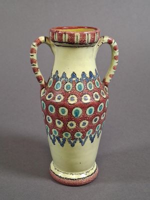 a red and white vase sitting on a gray surface