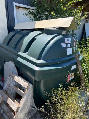 une grande poubelle verte à côté d'un tas de bois