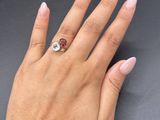 someone is holding a ring with a red stone on it