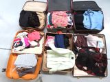 plusieurs valises ouvertes, contenant des vêtements, posées par terre