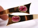 pair of gold tone cuff bracelets with pink stones on each side