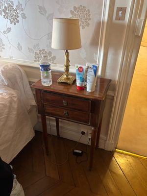 une petite table sur laquelle se trouve une lampe, dans une chambre