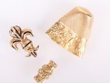 deux bijoux en or posés sur une surface blanche, sur fond blanc