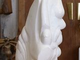 une sculpture blanche posée sur une table en bois dans une pièce