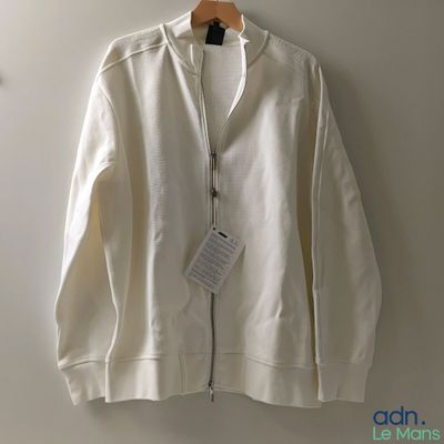 the white jacket is hanging on a hanger on the wall