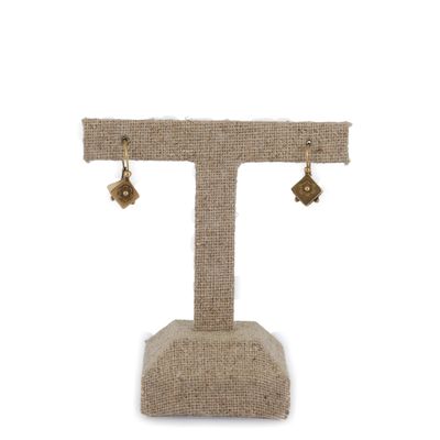 une paire de boucles d'oreilles posée sur un présentoir, sur fond blanc