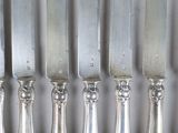 five silver knives on a table next to each other