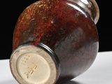 a brown vase with a brown lid sitting on a white surface