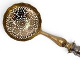 a gold spoon with a handle on a white surface