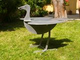 a metal bird that is standing in the grass