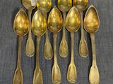 six cuillères en or sont alignées sur une table