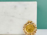 gold plated sunburst brooch on a white marble surface