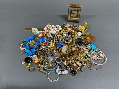 a pile of jewelry sitting on a table with a clock in the background