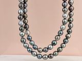 un gros plan d'un collier de perles noires sur fond rose