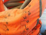 un sac orange auquel est attaché un tuyau, posé au sommet d'un tas d'ordures