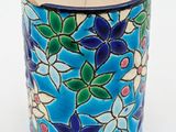 a blue vase with flowers on it on a white surface