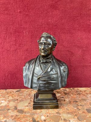 a bronze bust of a man sitting on top of a marble table