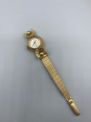 une montre-bracelet en or avec un cadran blanc sur une surface blanche