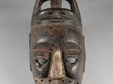 a close up of a wooden mask on a white surface