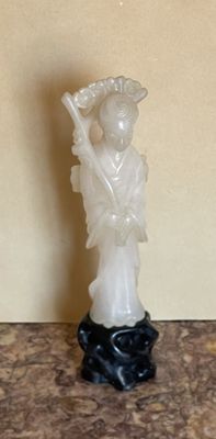 une statue représentant une femme tenant un éventail, posée sur une table