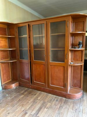 une bibliothèque en bois avec des portes vitrées, placée dans un coin de la pièce
