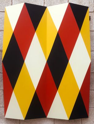 yellow, red, black and white argyle pattern on a brick wall