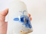 une main tenant une tasse ornée d'un motif bleu et blanc