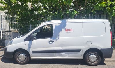 a white van parked in a parking lot with trees in the background