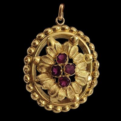 an image of a close up of a gold pendant with a flower