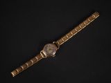 a close up of a gold watch on a black surface