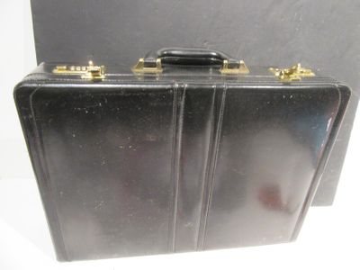 a black suitcase with gold handles on a white surface