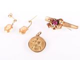 three pieces of jewelry including a gold pendant, earrings, and a coin