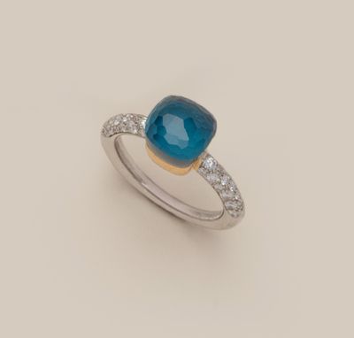 gros plan d'une bague avec une pierre bleue et des diamants