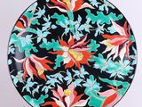 un gros plan sur une assiette noire ornée de fleurs colorées