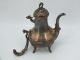 an antique silver teapot with a bird on the handle