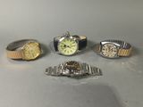 four different watches are sitting on a table next to each other