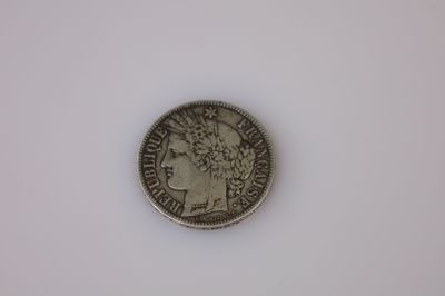 une pièce d'argent posée sur une surface blanche, sur fond blanc