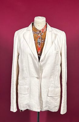 a white jacket on a mannequin stand against a red wall