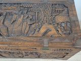 a wooden box with carvings on it sitting on a tile floor