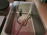 a metal sink with a red handle in the middle of the room