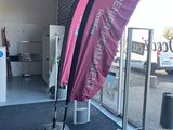un drapeau rose hissé sur un mât devant un magasin