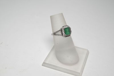 un gros plan d'une bague sertie d'une pierre verte, posée sur un socle
