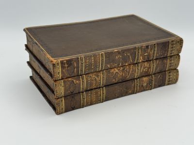 trois vieux livres empilés sur une surface blanche