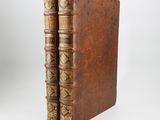an old book with two leather bindings sitting on top of each other